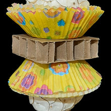 Load image into Gallery viewer, Two super soft sola balls nestled inside colorful paper cupcake liners with a cardboard honeycomb block in the middle and mahogany chunks on both ends. Strung on stainless steel wire with small wood beads and pony beads.
