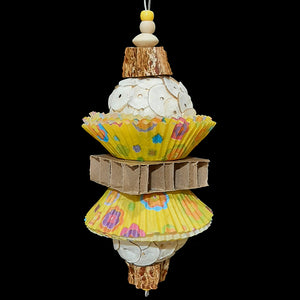 Two super soft sola balls nestled inside colorful paper cupcake liners with a cardboard honeycomb block in the middle and mahogany chunks on both ends. Strung on stainless steel wire with small wood beads and pony beads.